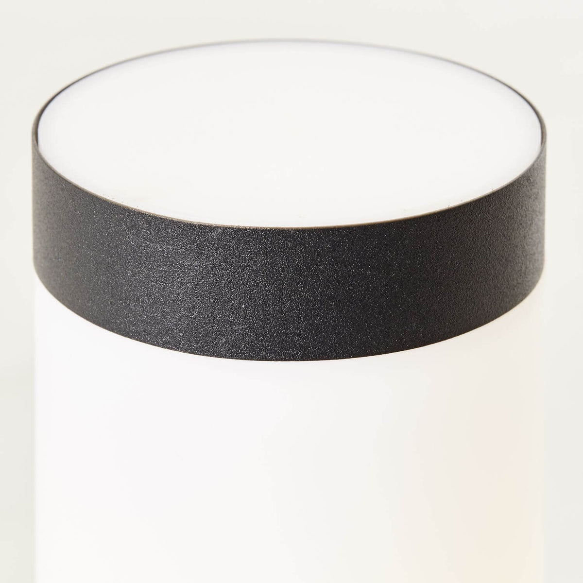 Gros plan sur le chapeau noir et le haut du diffuseur blanc de la borne.