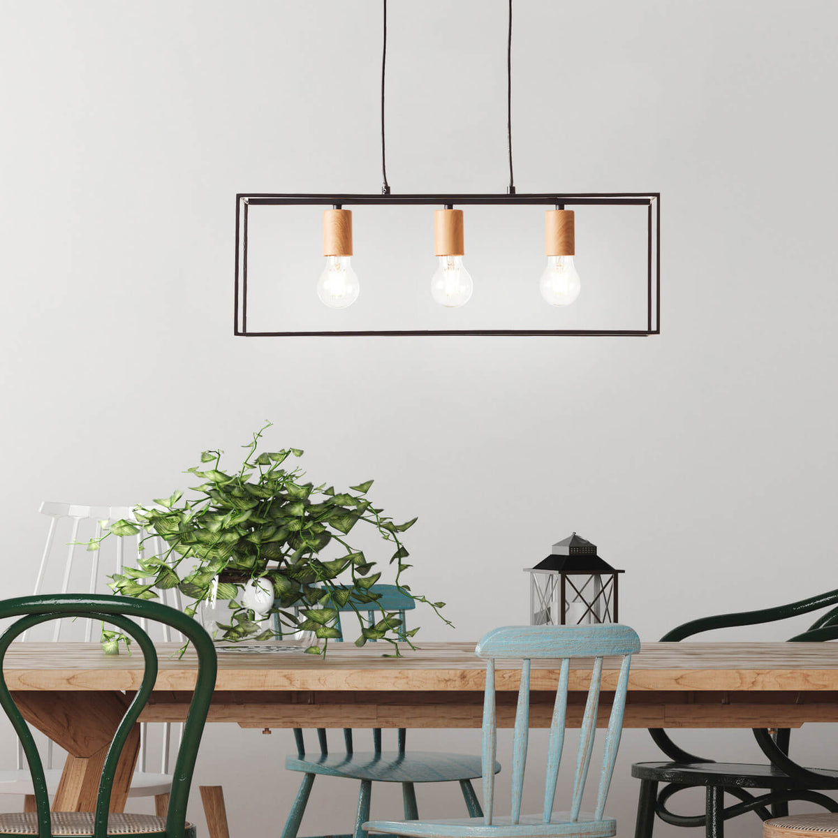 Mise en ambiance au-dessus d'une table à manger en bois, luminaire allumé avec plantes vertes.