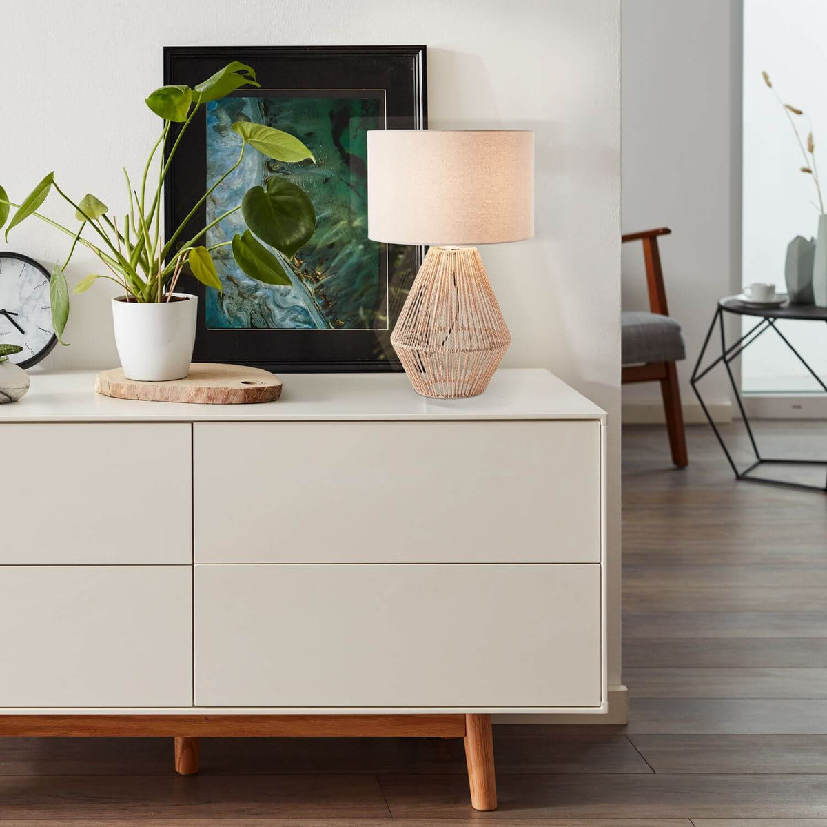 Lampe posée sur un buffet blanc dans un salon moderne, près d'une plante verte.