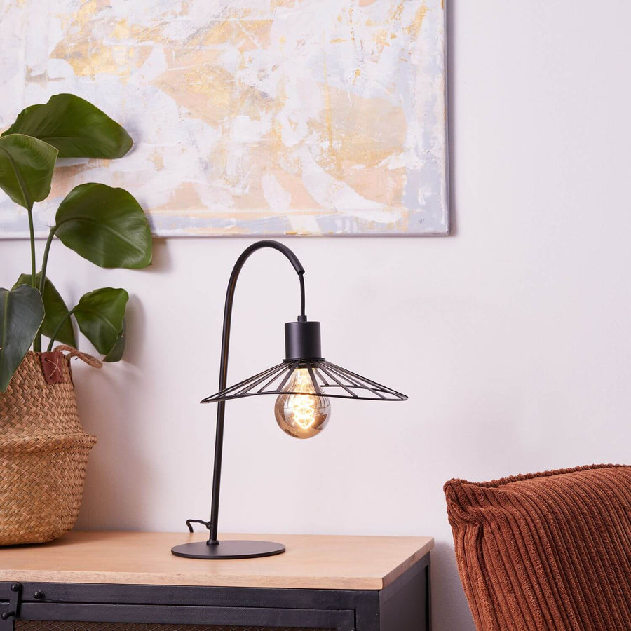 Lampe allumée dans un intérieur avec plante verte et coussin terracotta