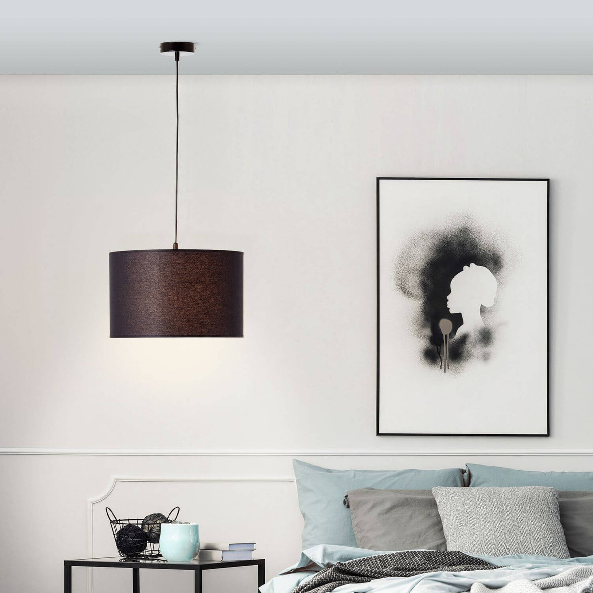 Suspension noire allumée dans une chambre, au-dessus d'une table de chevet et d'un lit