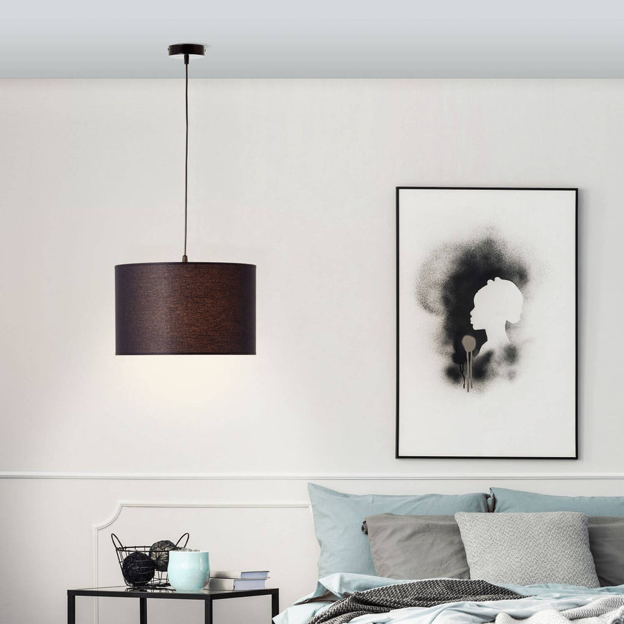Suspension noire allumée dans une chambre, au-dessus d'une table de chevet et d'un lit