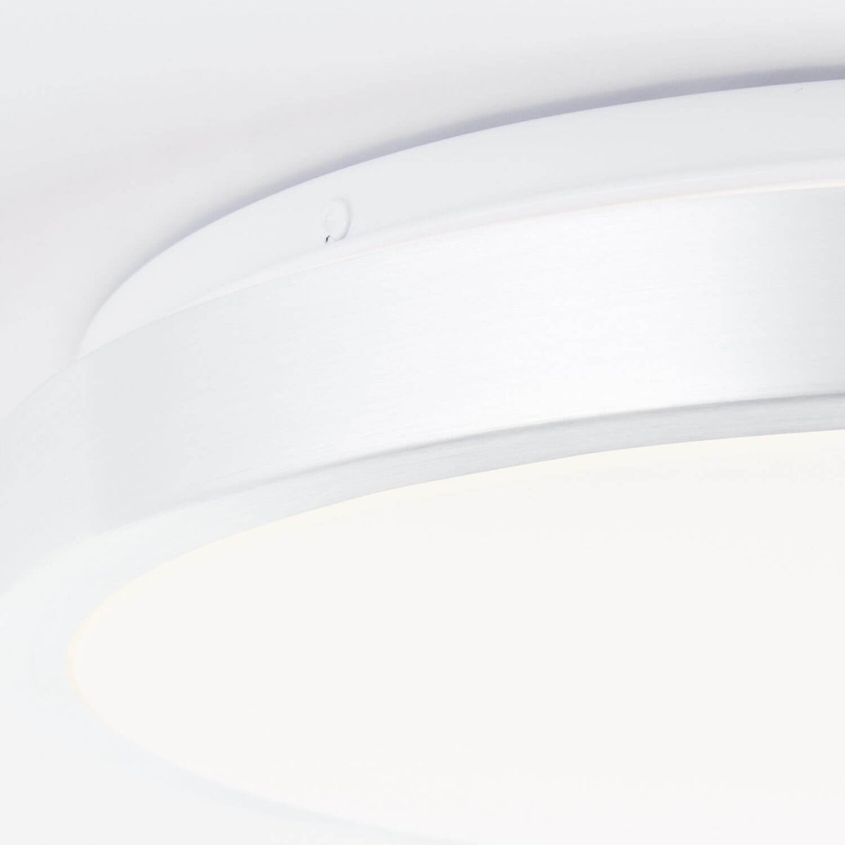 Détail rapproché de la bordure et du diffuseur blanc du luminaire.