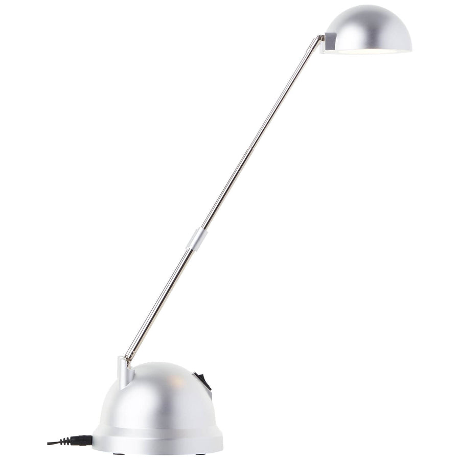 Lampe à poser argentée vue de côté, tige fine inclinée et réflecteur en dôme.