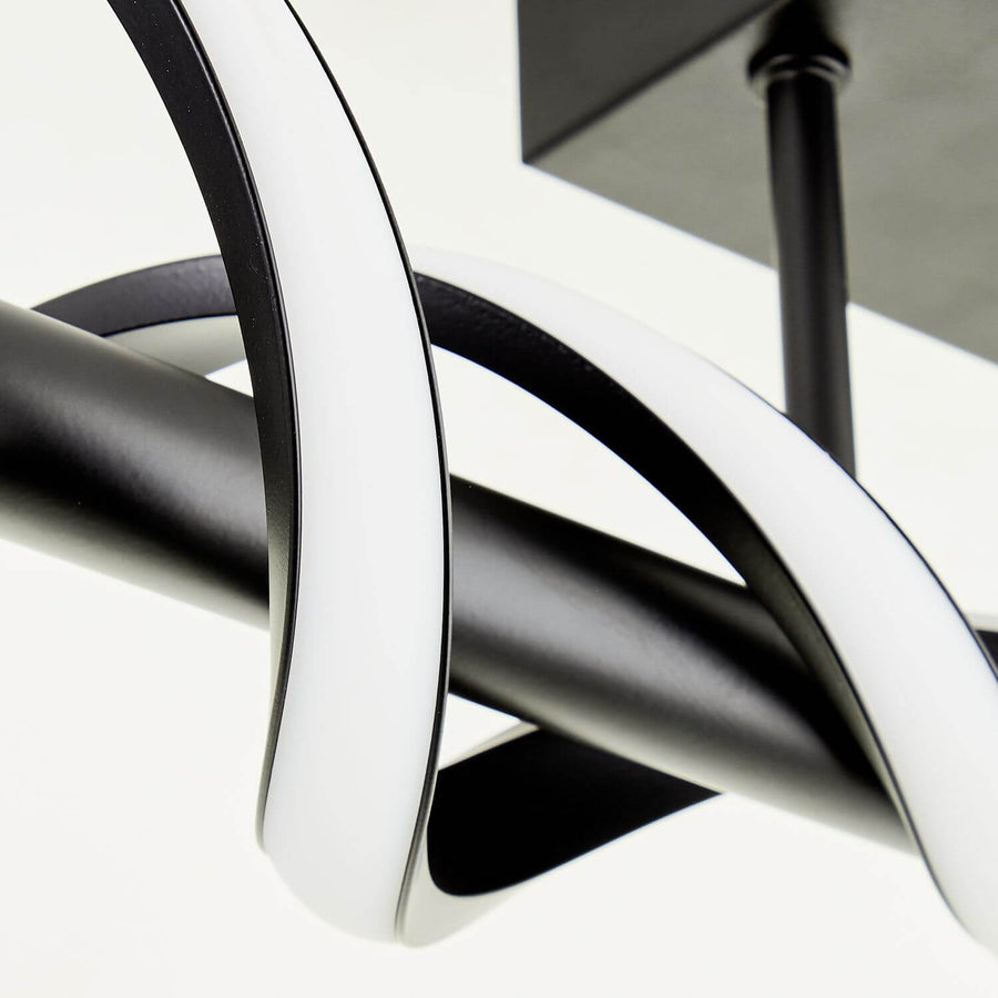 Détail rapproché de la finition noire et du diffuseur blanc du luminaire spiralé.