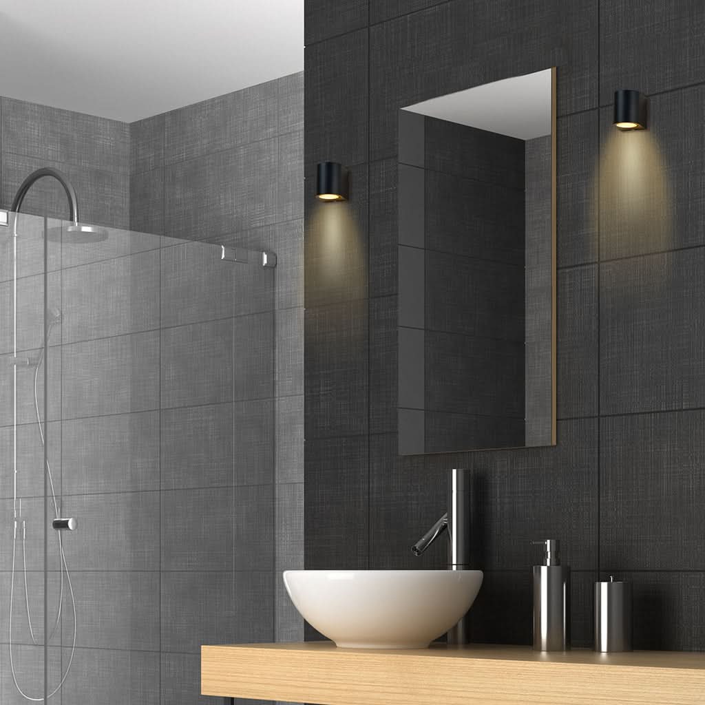 Deux appliques noires installées en salle de bain de part et d'autre du miroir