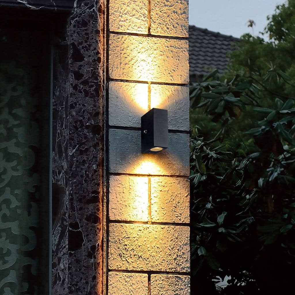 Mise en ambiance nocturne sur mur en pierre, le luminaire éclaire vers le bas.