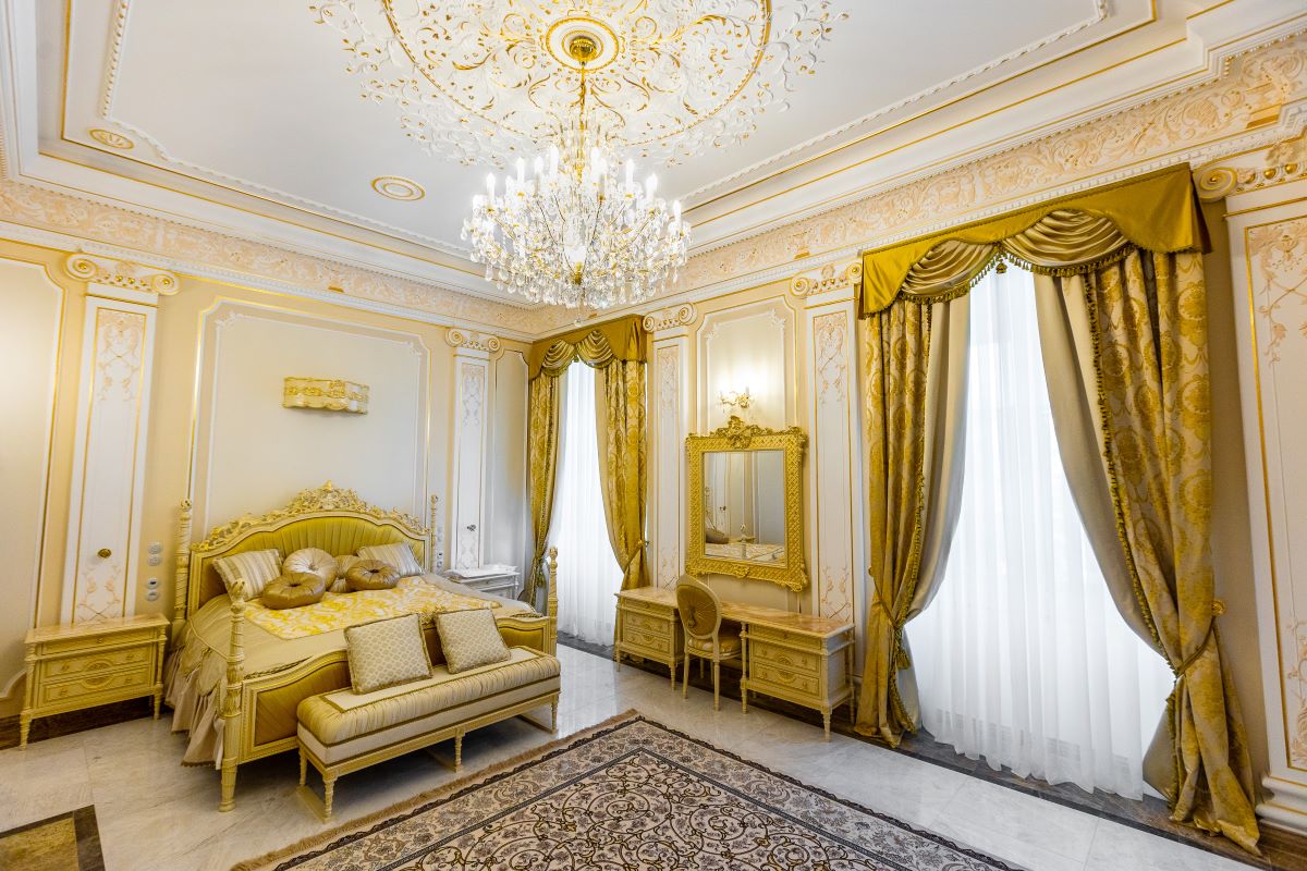 Vue large d'une chambre dorée avec le lustre au plafond et rideaux jaunes