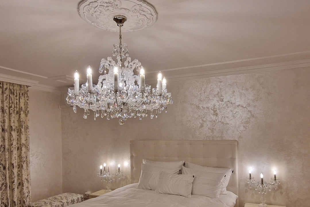 Mise en ambiance du lustre allumé au-dessus d'un lit dans une chambre claire.