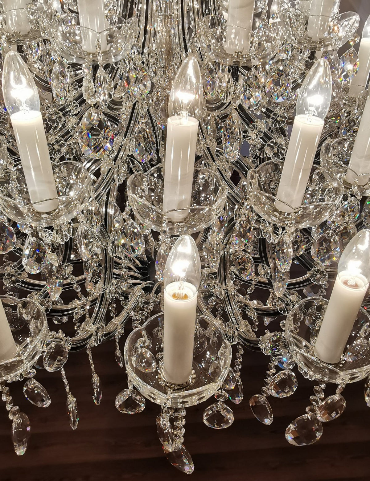 Gros plan sur les douilles blanches, bougies et pampilles de cristal suspendues.