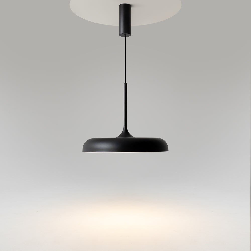 Abat-jour noir allumé projetant un halo lumineux chaud vers le bas