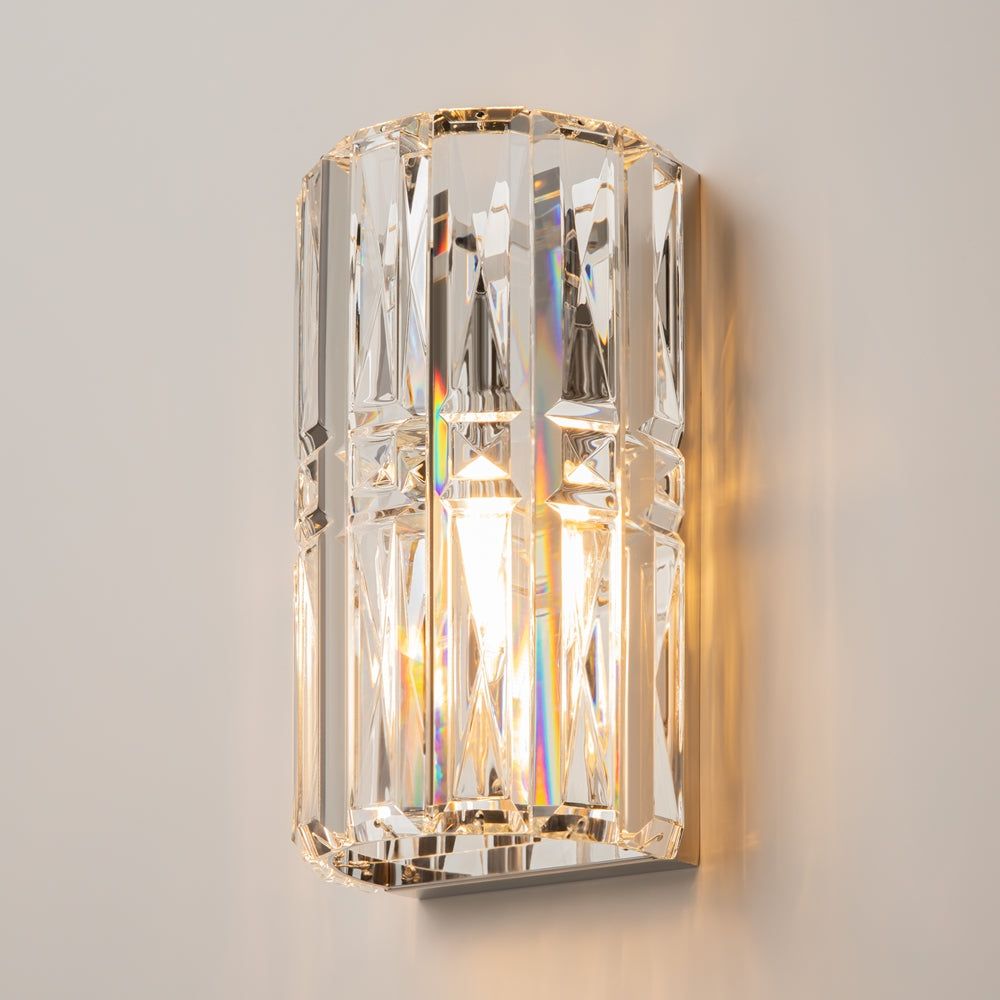 Applique allumée fixée au mur, halo doré et reflets irisés sur le verre