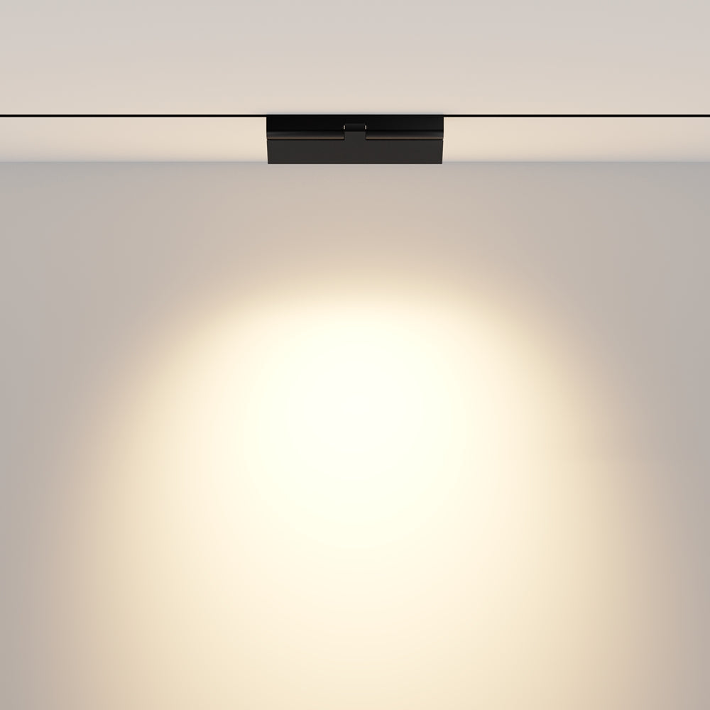 Vue frontale du spot fixé au plafond projetant un halo lumineux sur le mur