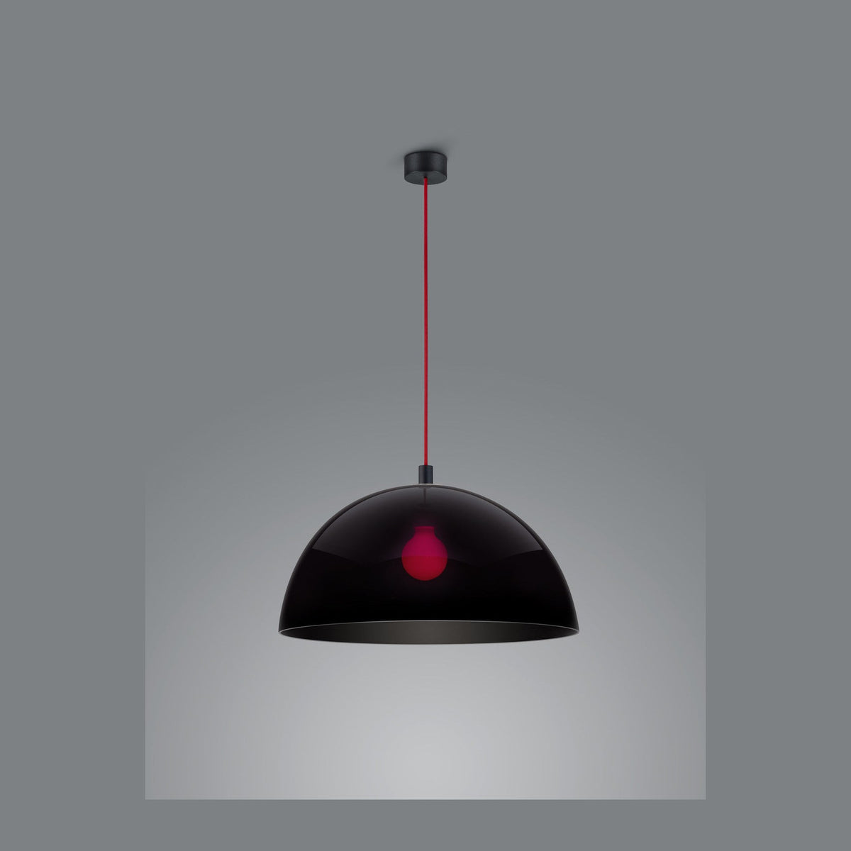 Suspension noire brillante de face sur fond gris, câble rouge et douille apparente