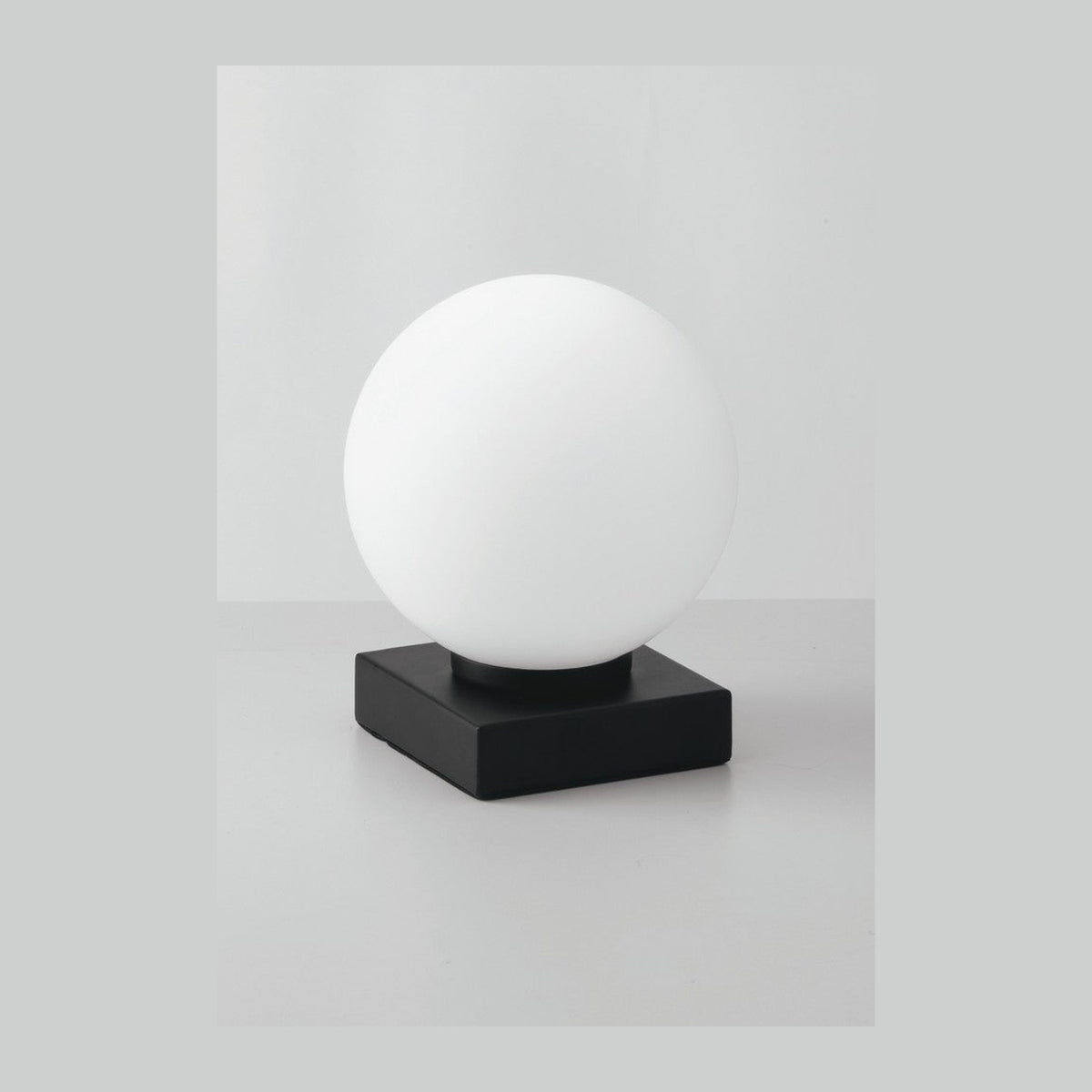 Lampe à poser de face, globe de verre blanc opaque sur socle carré noir