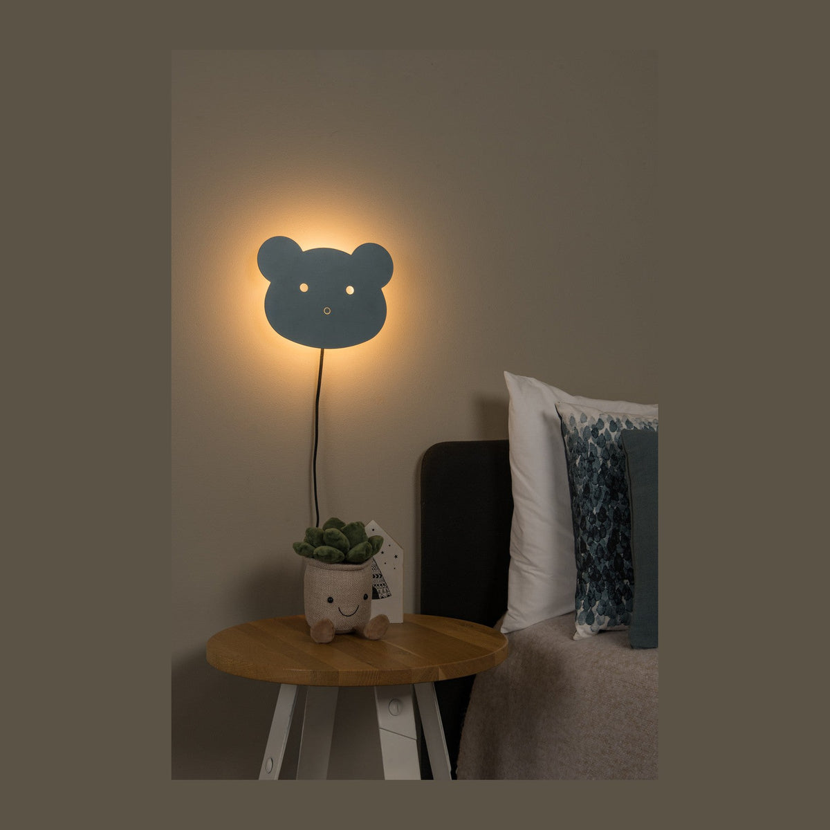 Mise en ambiance de l'applique murale tête d'ours bleue allumée dans une chambre.