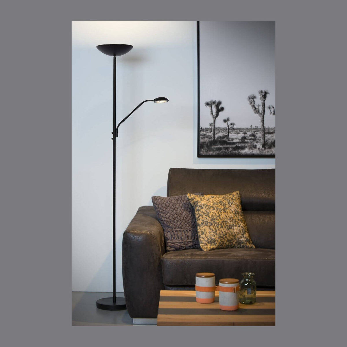 Lampadaire noir allumé dans un salon, près d'un canapé en cuir marron