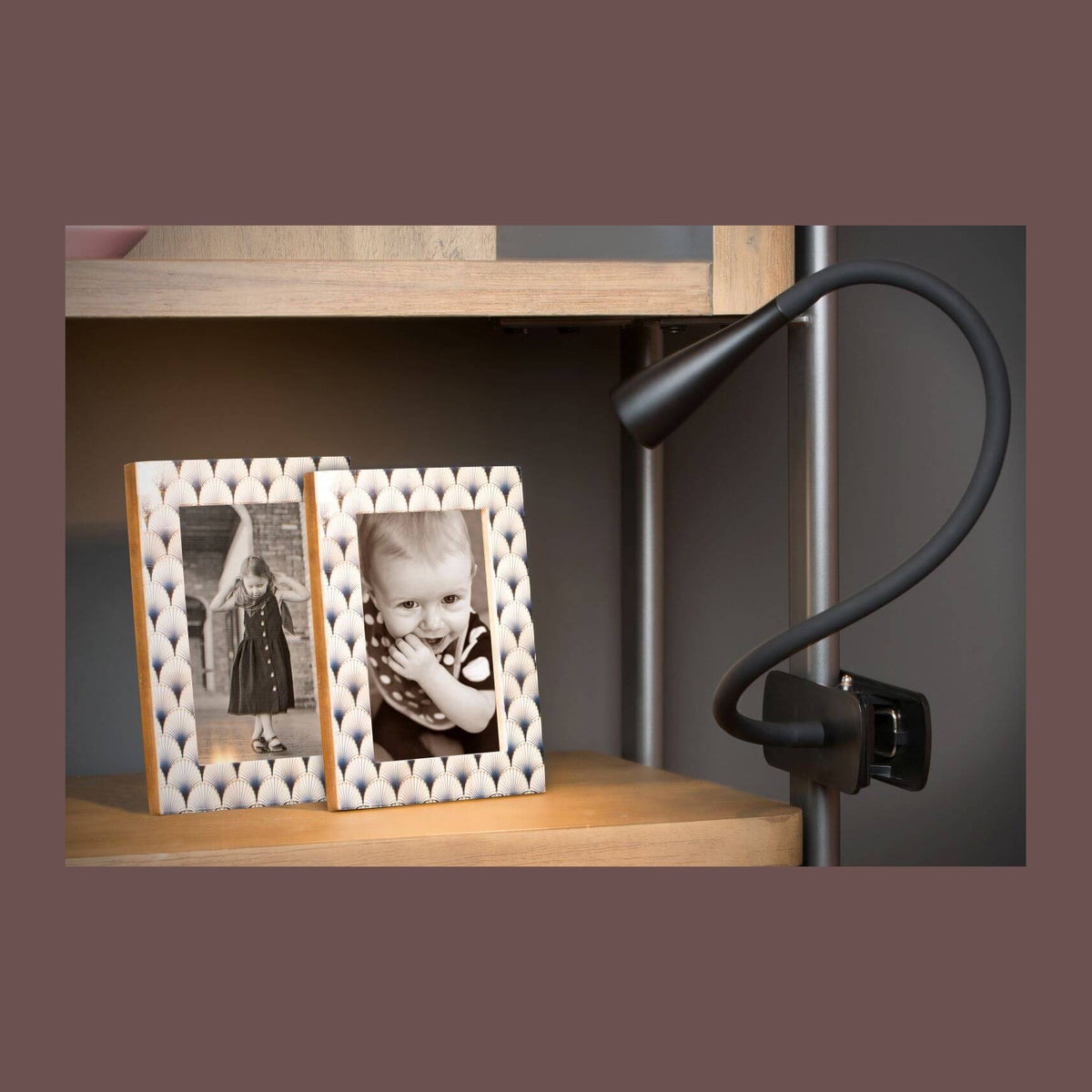 Lampe noire pincée sur étagère en bois, encadrements photo en ambiance