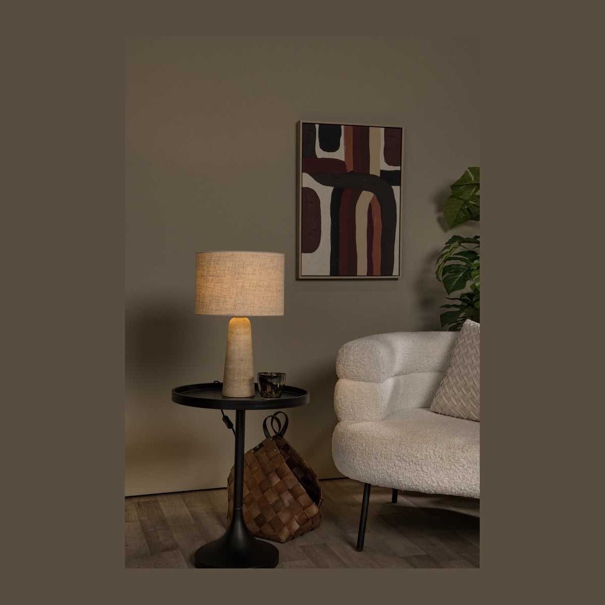 Lampe à poser en travertin éclairée sur une table d'appoint noire dans un salon
