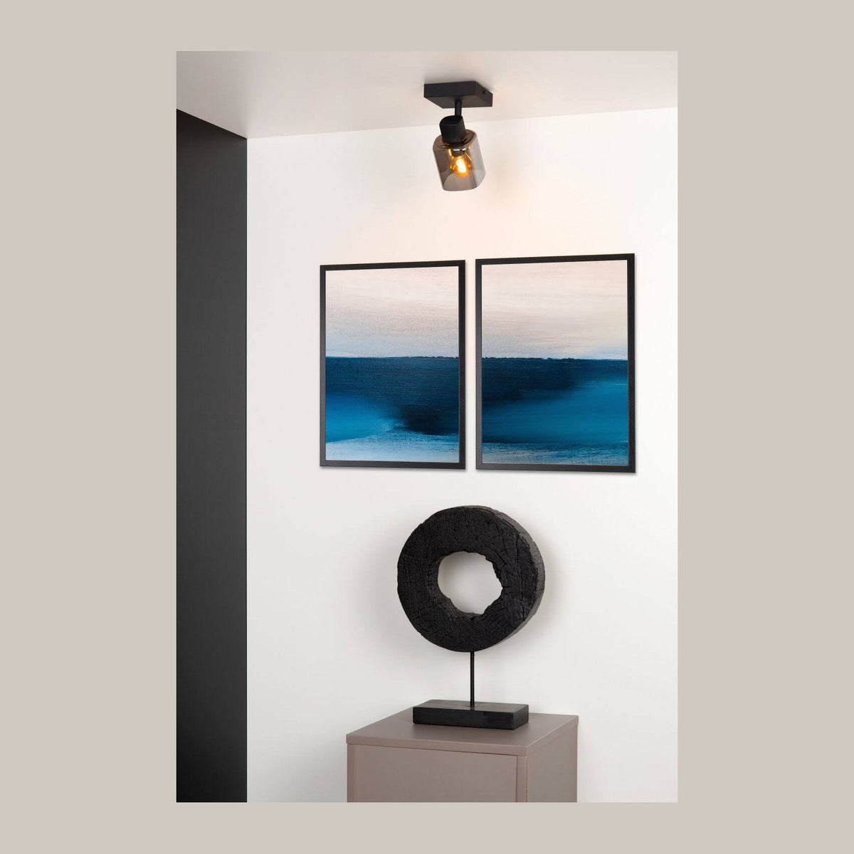 Plafonnier noir fixé au plafond, verre fumé, dans un intérieur avec cadres bleus
