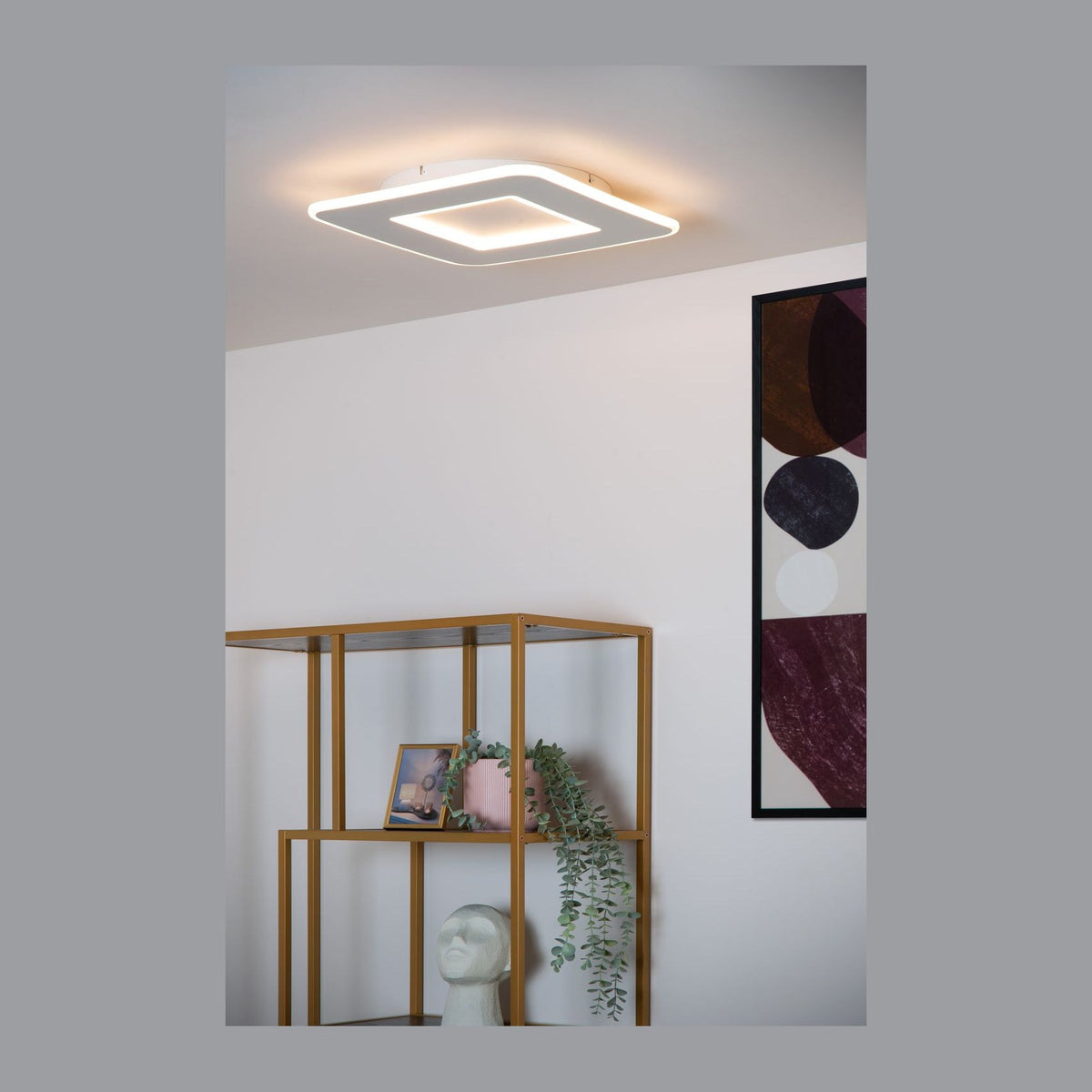 Plafonnier carré blanc allumé au plafond, au-dessus d'une étagère en métal doré