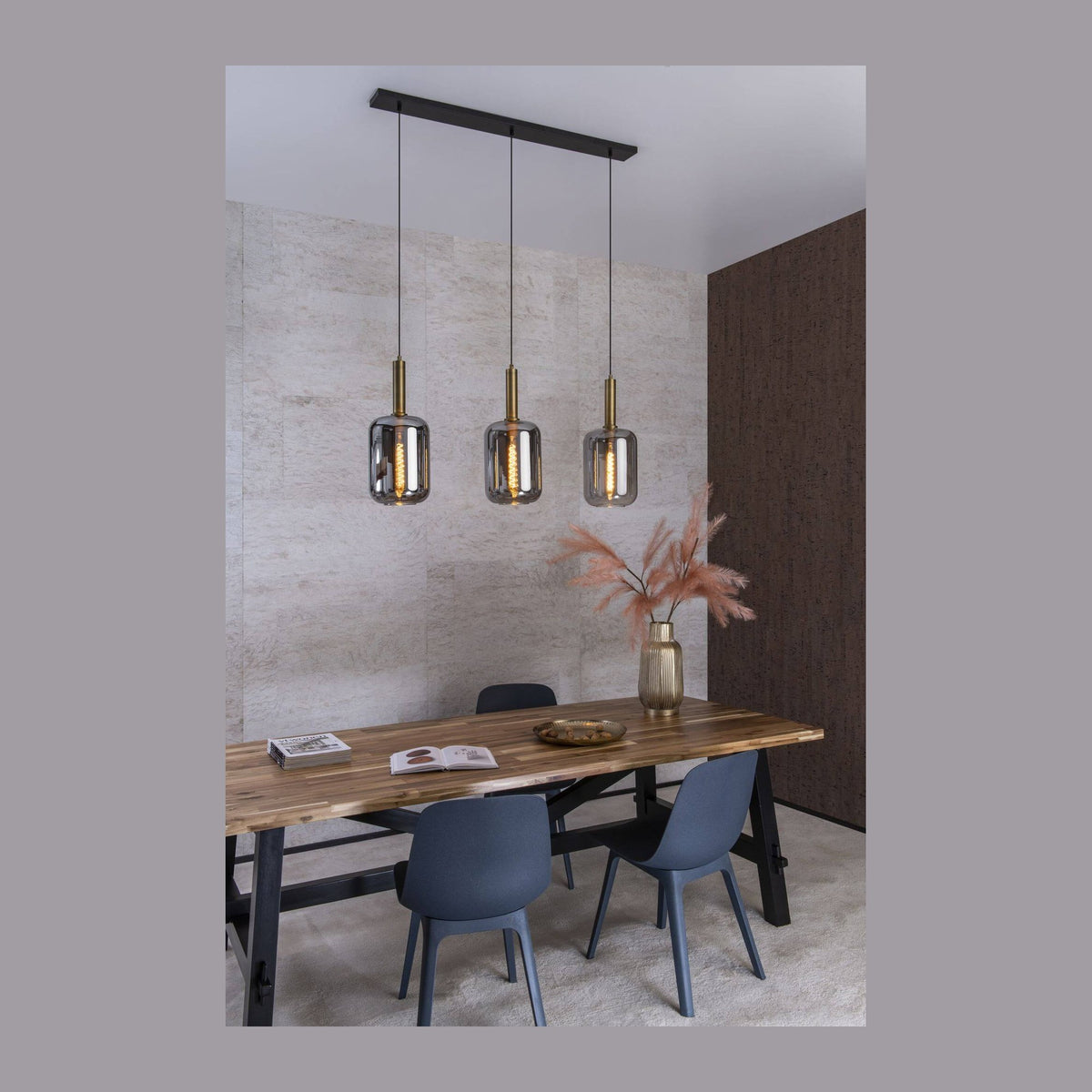Suspension trois lumières en verre fumé au-dessus d'une table en bois clair