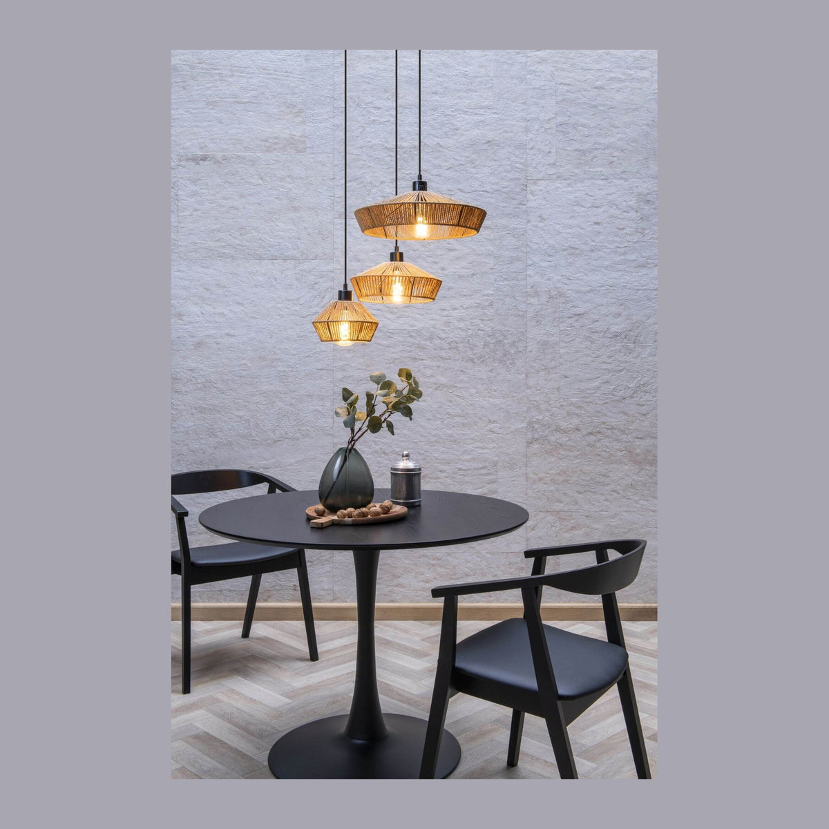 Suspension trois lumières en rotin suspendue au-dessus d'une table ronde noire en ambiance