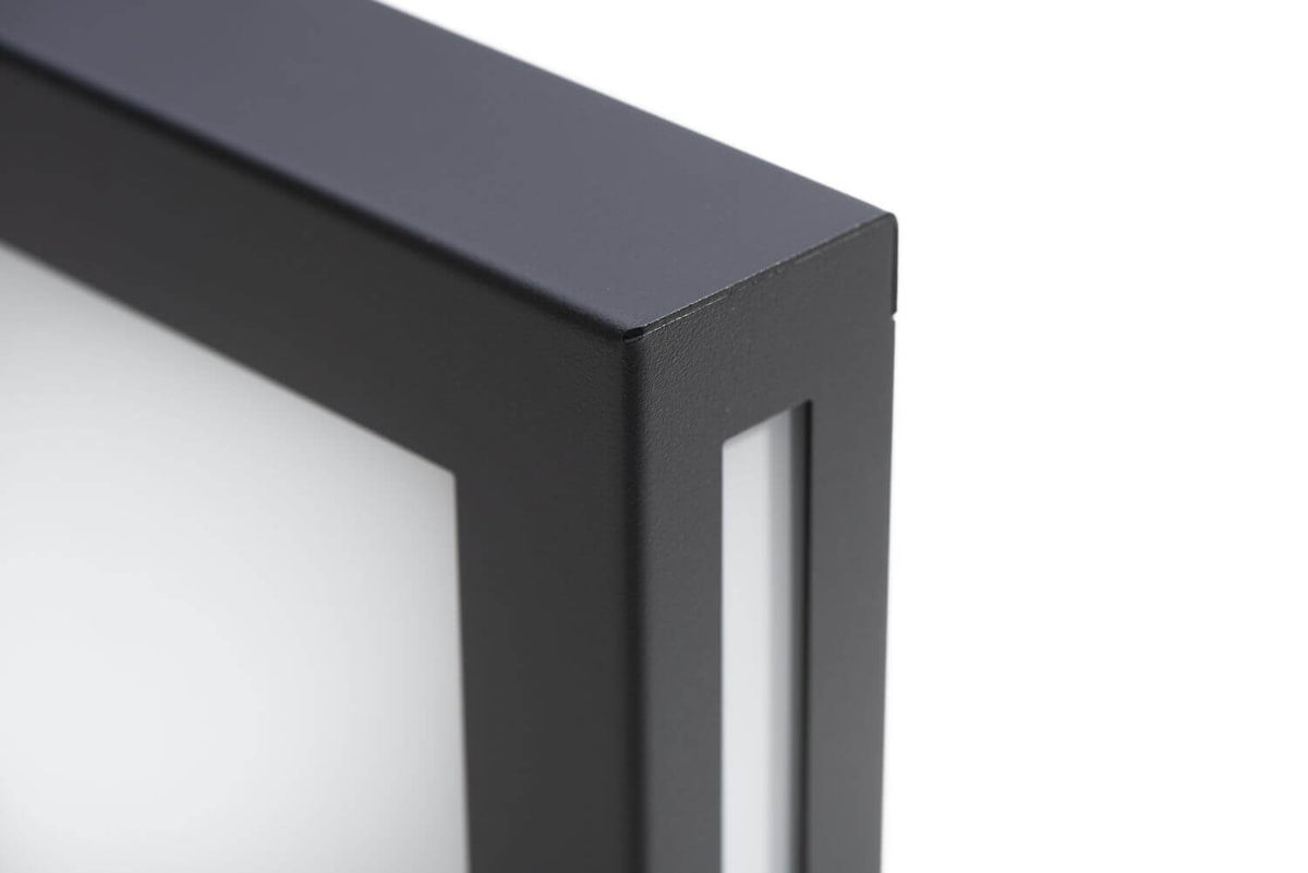 Détail du coin de l'applique : cadre anthracite texturé et diffuseur blanc opaque, finition soignée.