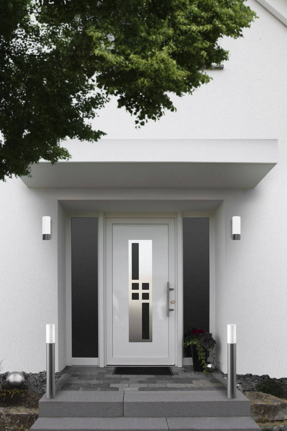 Mise en ambiance de deux luminaires au sol de chaque côté d'une entrée de maison.