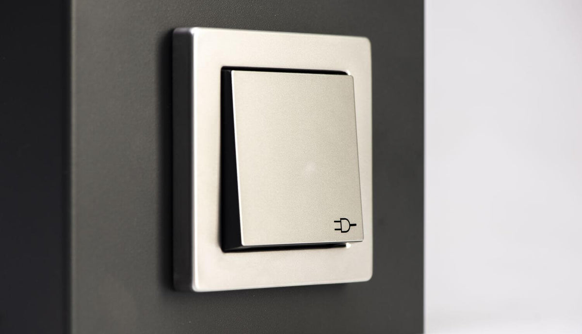Gros plan sur l'interrupteur gris intégré au luminaire extérieur anthracite.