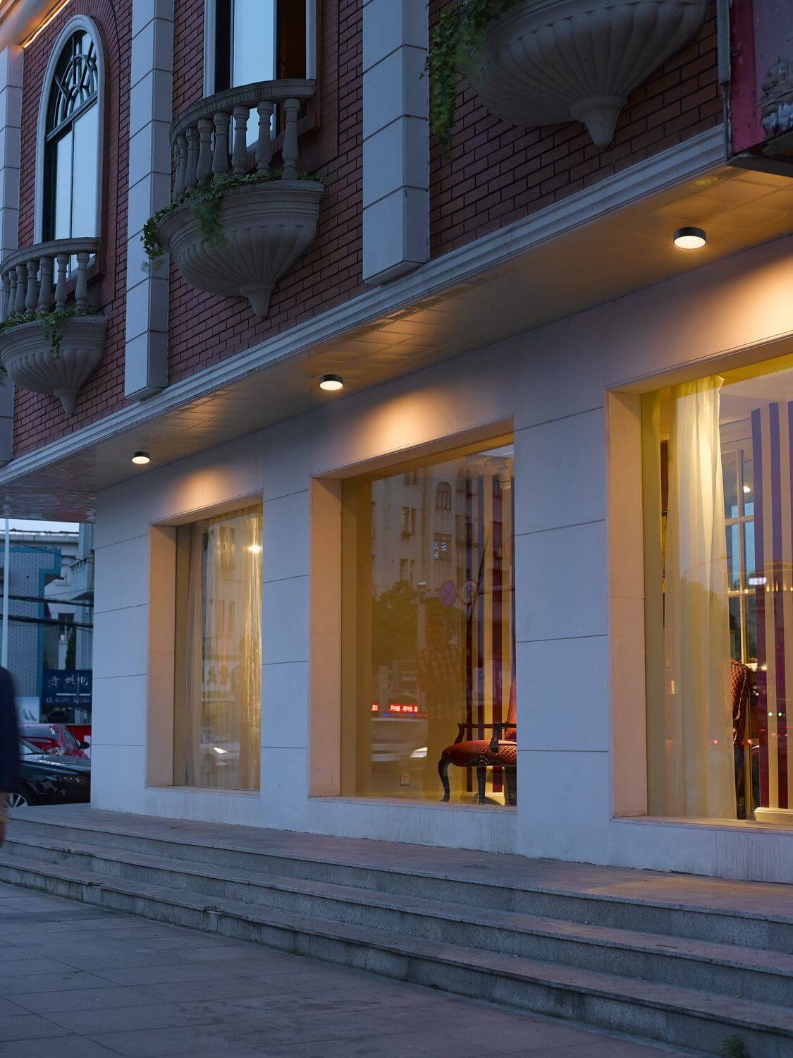 Mise en ambiance nocturne sous auvent, deux luminaires éclairant une vitrine