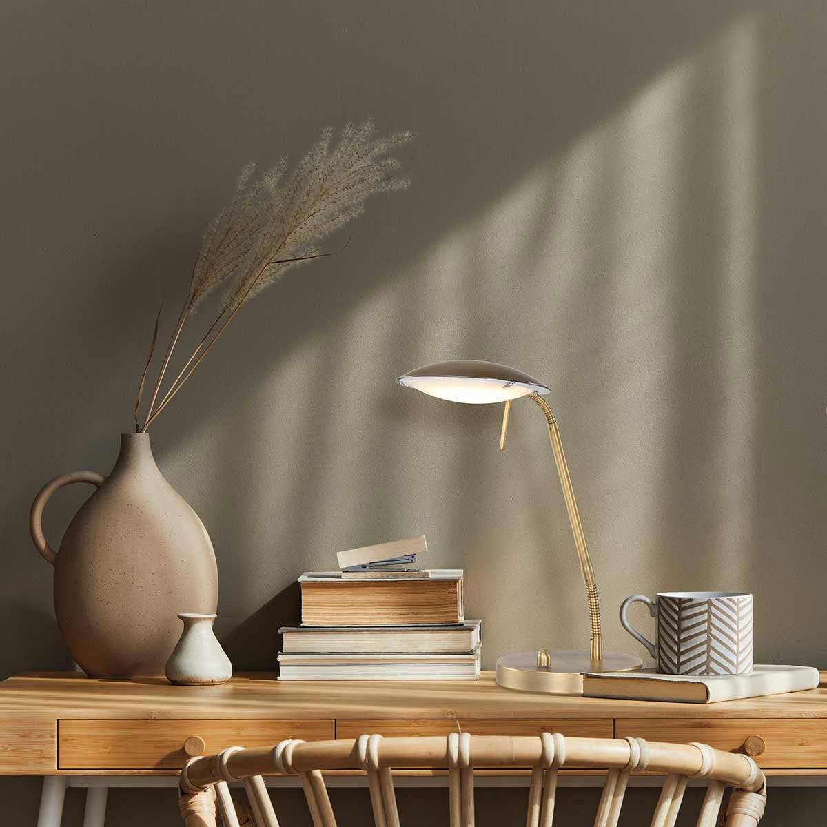Mise en ambiance sur un bureau en bois avec livres, vase et lumière allumée