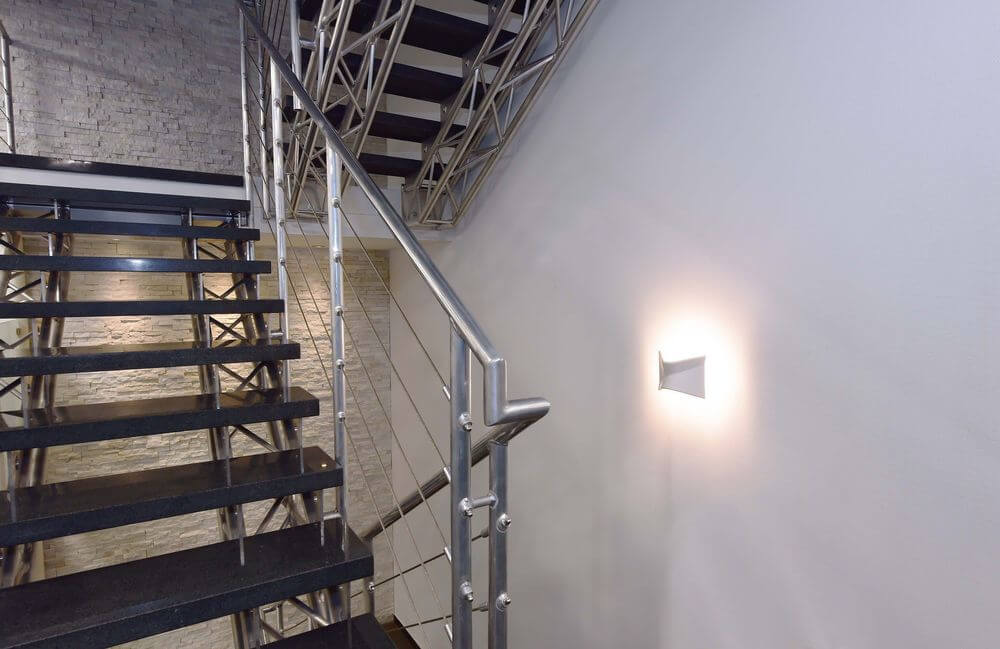 Mise en ambiance de l’applique allumée sur un mur près d’un escalier métallique