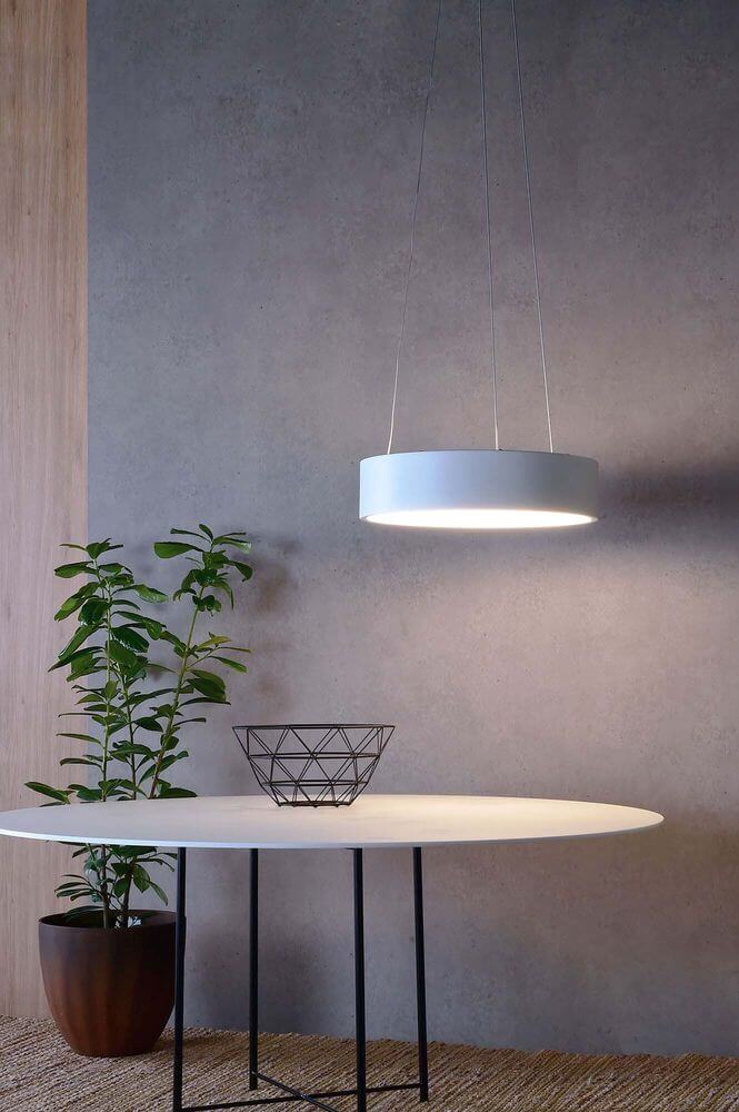 Mise en ambiance au-dessus d'une table blanche, avec plante verte et mur gris.