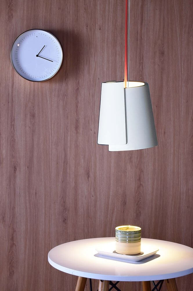 Suspension allumée au-dessus d'une table ronde devant un mur en bois