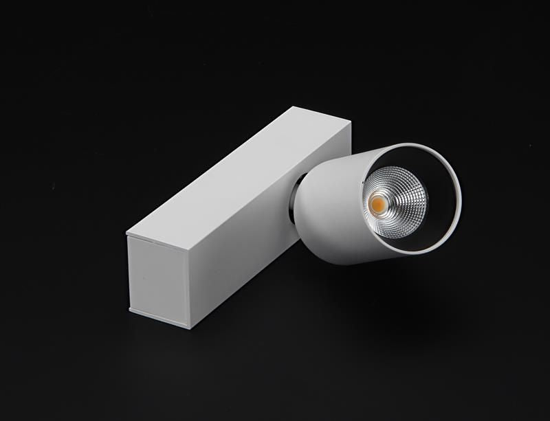 Spot blanc orientable sur socle rectangulaire, tête cylindrique vue de trois quarts