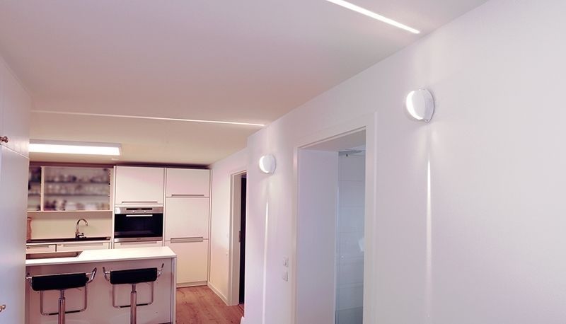 Mise en ambiance dans une cuisine blanche avec deux appliques murales allumées