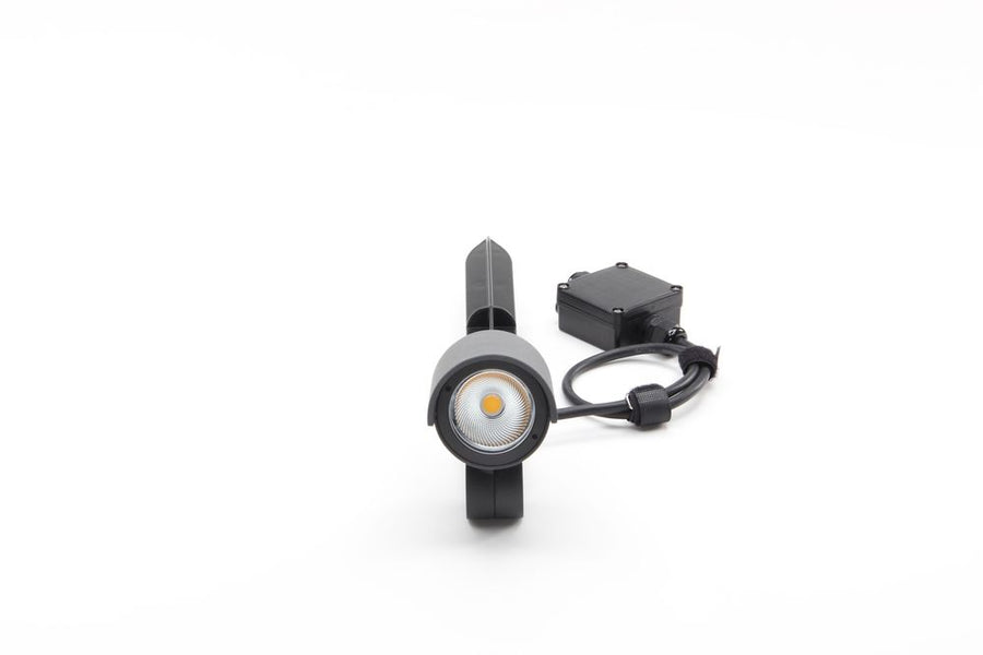 Vue de face du projecteur gris, lentille LED ronde et câble avec boîtier étanche.