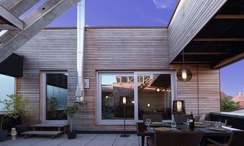 Terrasse en bois avec la suspension noire suspendue sous l’auvent, près de la table.