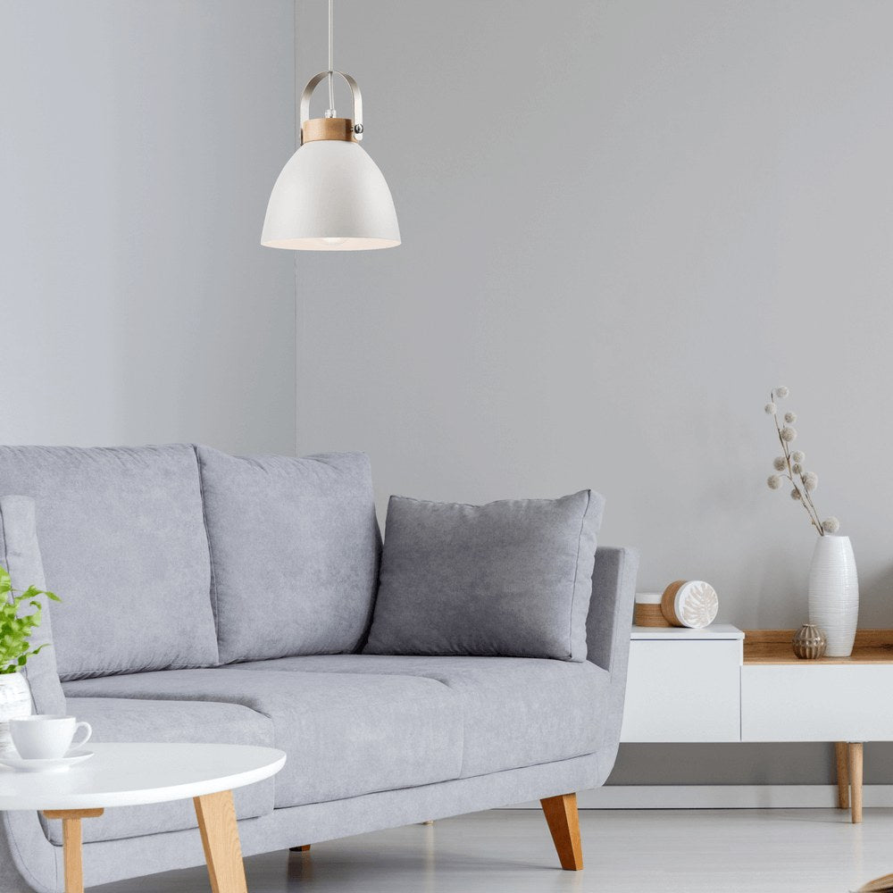 Mise en ambiance dans un salon gris clair, suspension allumée au-dessus d'un canapé.