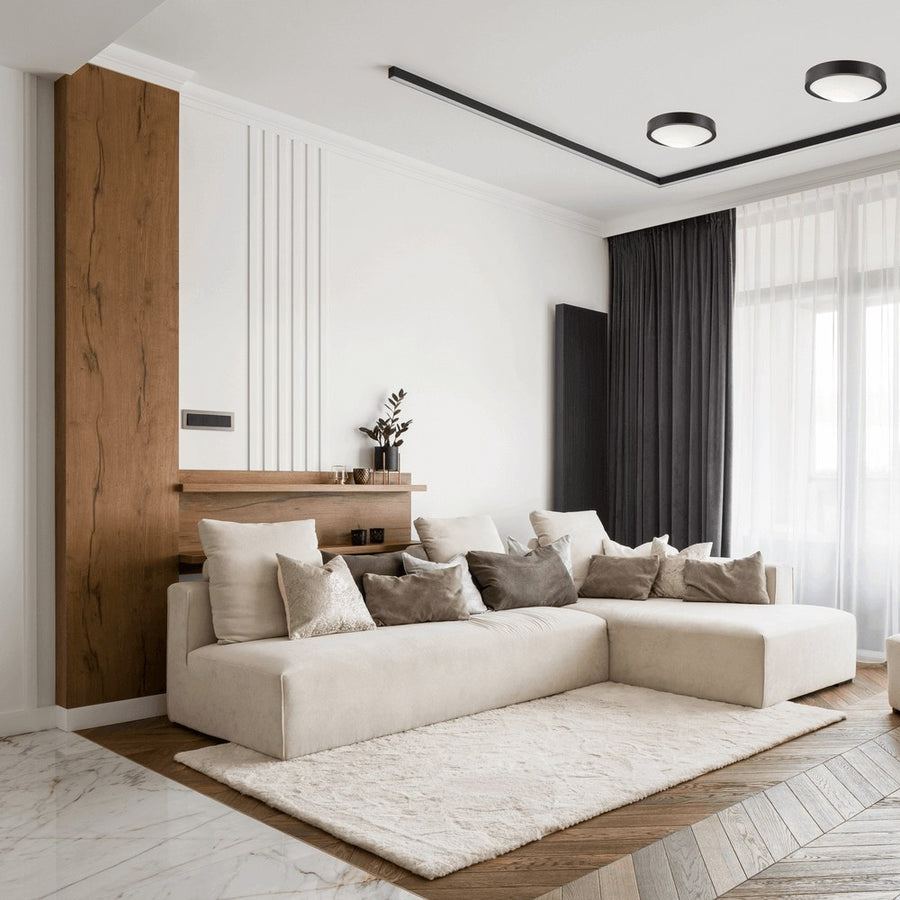 Plafonniers noirs au plafond dans un salon clair avec mur en bois et canapé beige.