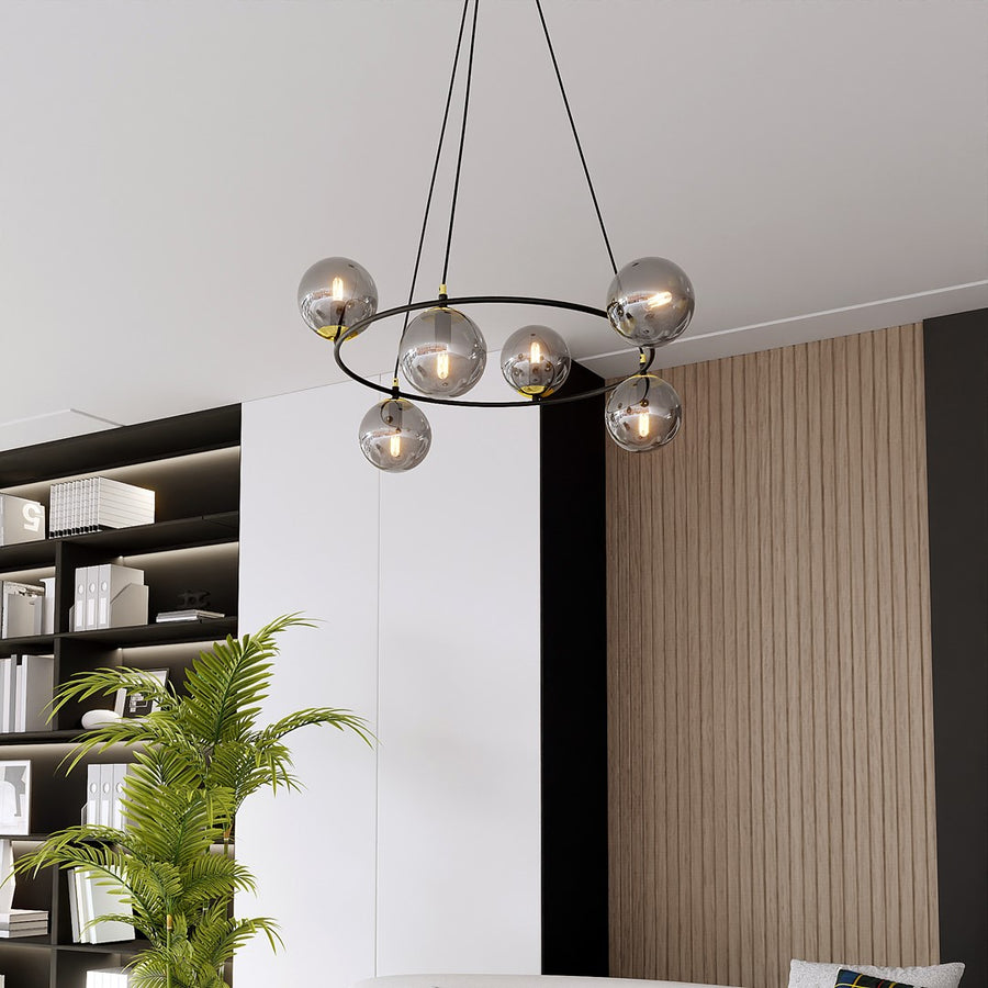 Suspension installée dans un salon, devant bibliothèque et plante, avec ampoules visibles allumées.