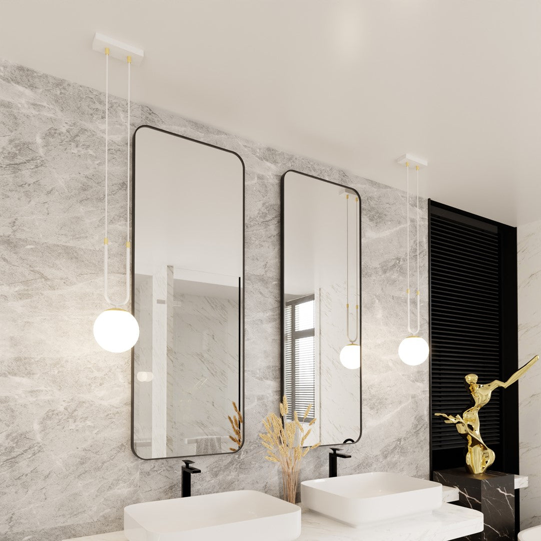 Luminaire suspendu au-dessus d’un lavabo, miroir noir et mur marbré clair