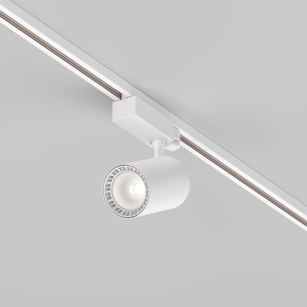 Spot blanc sur rail vu de trois quarts, projecteur allumé dans un intérieur clair