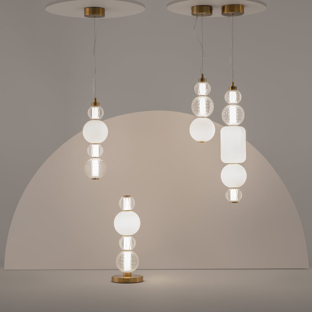 Mise en ambiance avec plusieurs suspensions et une lampe à poser assortie sur fond beige