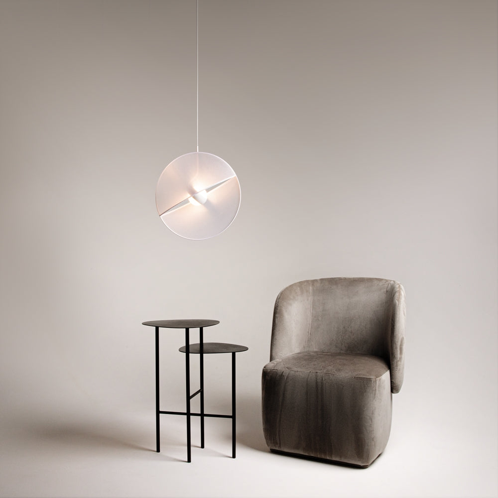 Mise en ambiance dans un salon, suspension allumée au-dessus d'une table et fauteuil