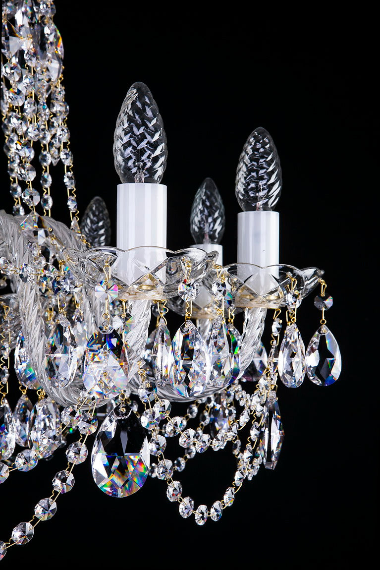 Gros plan sur les détails du lustre avec bobèches, ampoules, pampilles et chaînettes en cristal.