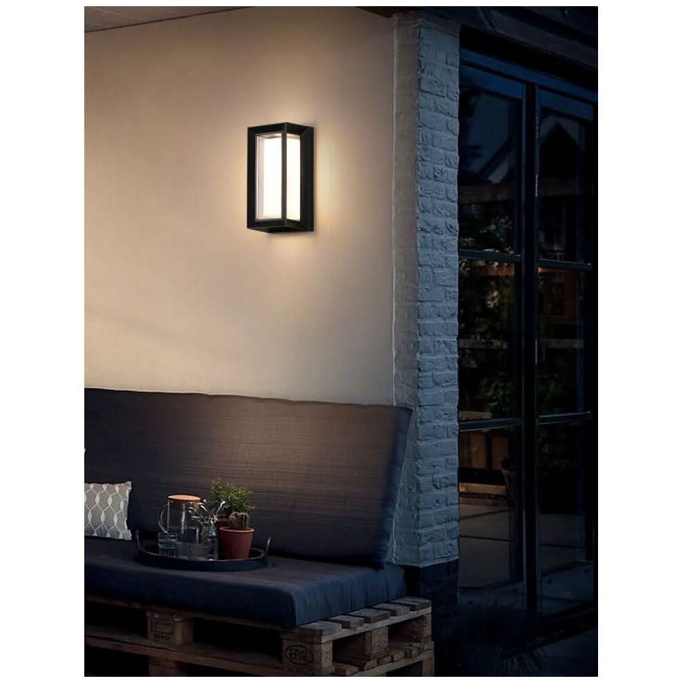 Mise en ambiance nocturne sur une terrasse, applique allumée au-dessus d'un banc en palettes