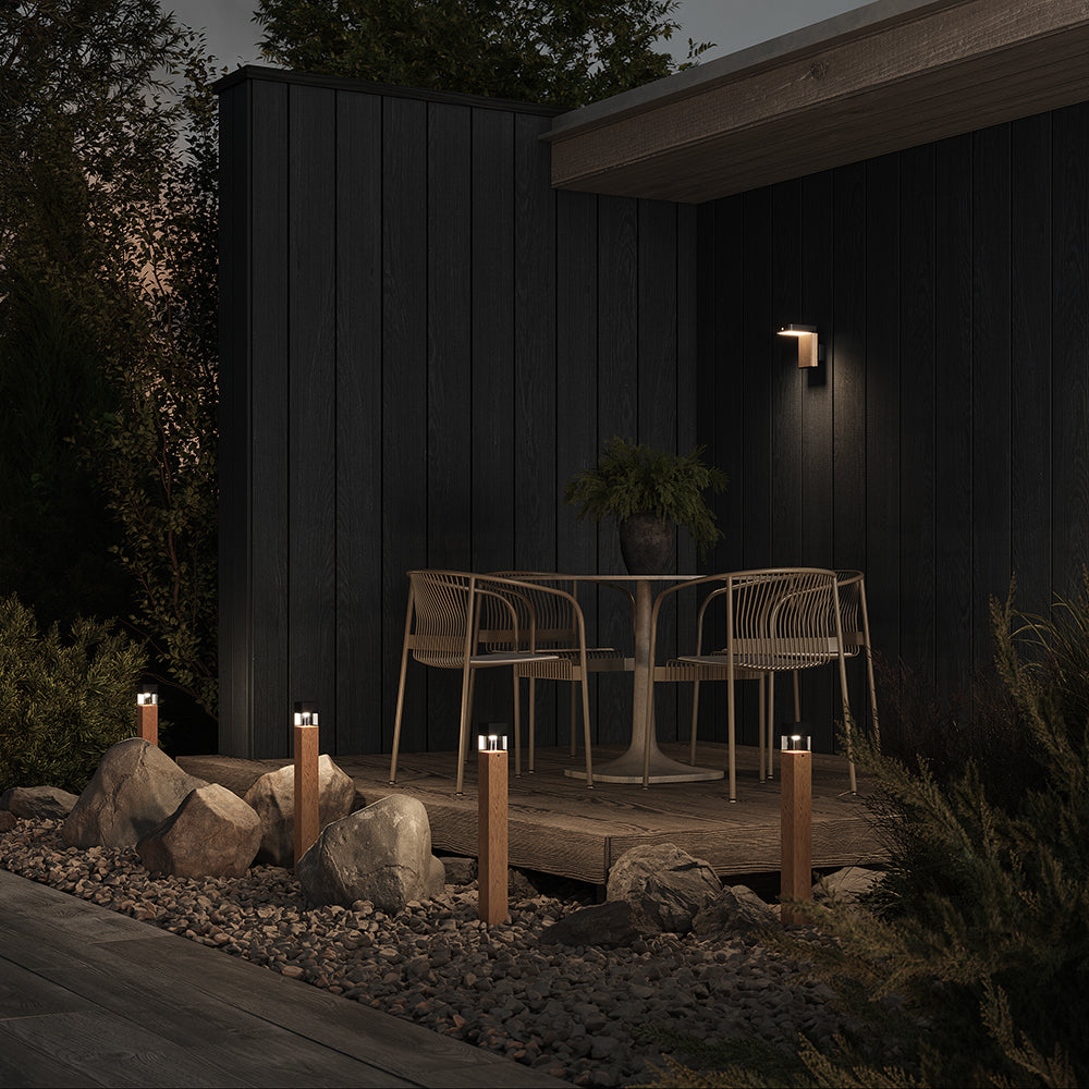 Ambiance nocturne : applique allumée sur terrasse en bois entourée de végétation