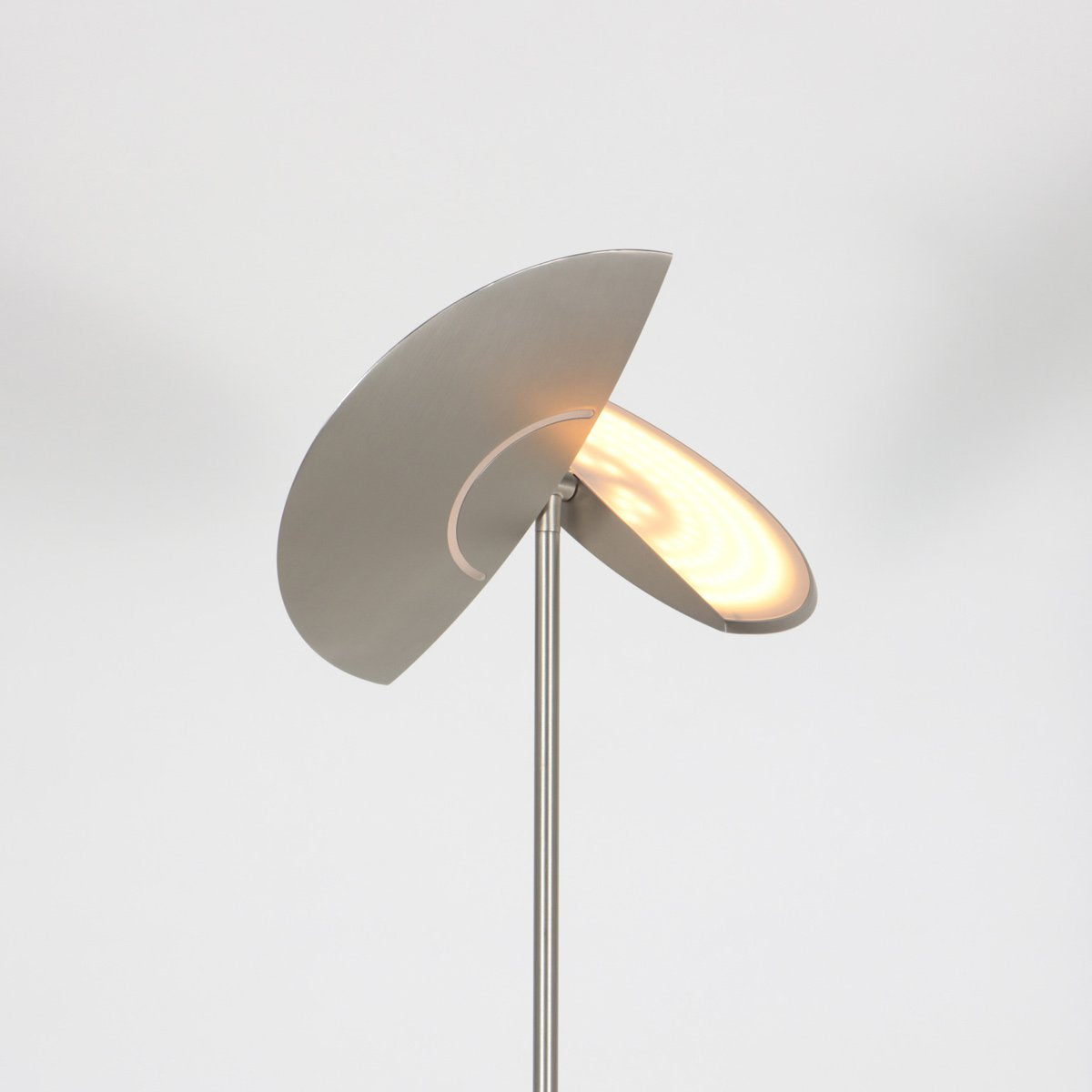 Détail du diffuseur supérieur allumé, disques superposés argentés et lumière chaude.